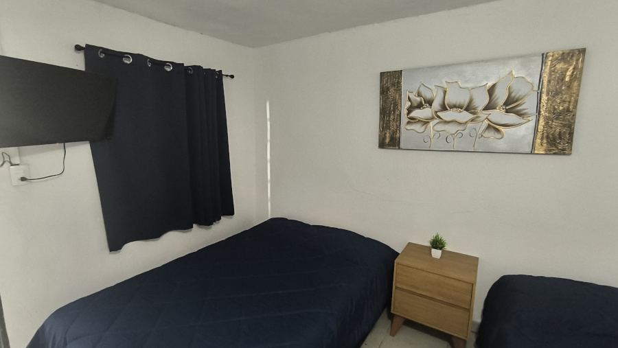 Imagen pequeña del buró, cuadro, cortina y una de las 2 camas