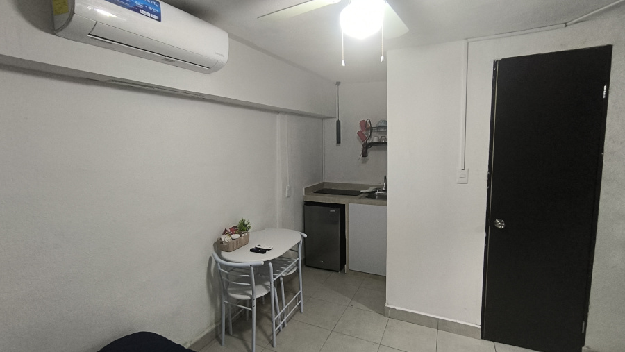 Imagen pequeña de la mesa, cocineta, el aire acondicionado y la puerta del baño