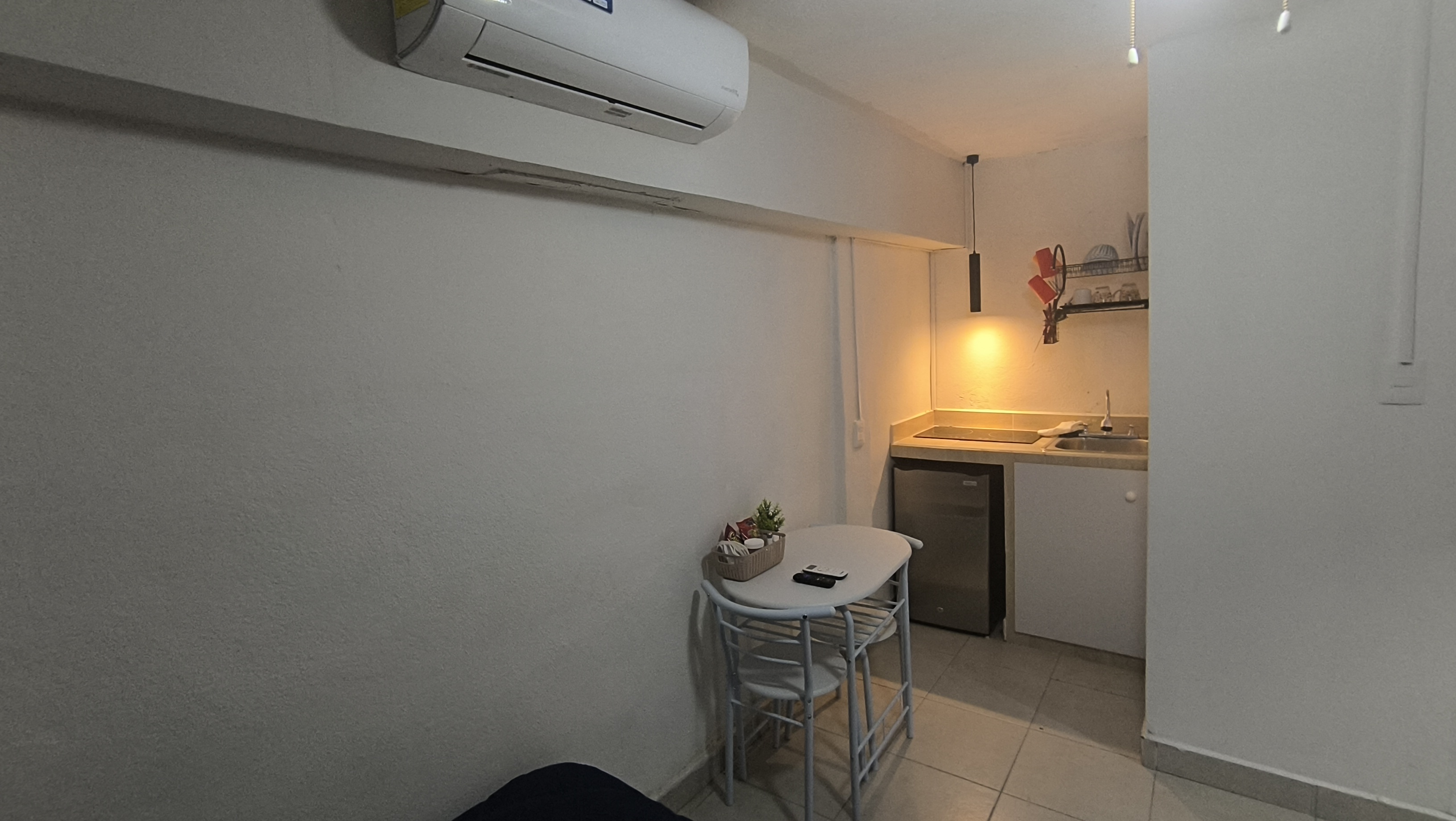 El Loft donde se ve la mesa, la cocineta y el aire acondicionado